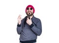 Positive handsome young bearded hipster in pink knitted hat smoking a pipe, expresses various emotions and shows Royalty Free Stock Photo