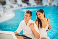 Positive happy couple relaxing by the swimming pool in luxury summer vacation resort.Enjoying time together in spa wellness center Royalty Free Stock Photo