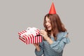 Positive happy girl with funny party hat opening gift box, peeking what bonus inside, smiling enjoying birthday Royalty Free Stock Photo