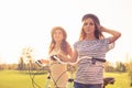 Positive happy girls with hat ride bicycles on the park Royalty Free Stock Photo