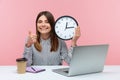 Positive happy woman office worker showing thumbs up holding big wall clock, looking at camera with toothy smile, time management Royalty Free Stock Photo