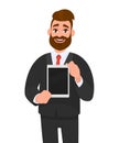 Positive happy young bearded business man showing/holding blank screen of digital tablet computer in hands. Modern technology. Royalty Free Stock Photo