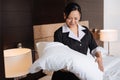 Positive hard working hotel maid looking at the pillow