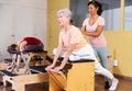 Hispanic woman pilates instructor helping aged woman exercising on wunda chair Royalty Free Stock Photo