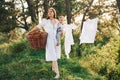 Positive housewife with hangs white clothes to dry. Young mother with her little son is outdoors in the forest. Beautiful sunshine Royalty Free Stock Photo