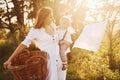 Positive housewife with hangs white clothes to dry. Young mother with her little son is outdoors in the forest. Beautiful sunshine Royalty Free Stock Photo