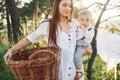 Positive housewife with hangs white clothes to dry. Young mother with her little son is outdoors in the forest. Beautiful sunshine Royalty Free Stock Photo