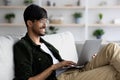 Positive indian guy chilling at home, using laptop Royalty Free Stock Photo