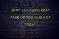 Positive inspiring quote on neon sign against brick wall dont let yesterday take up too much of today Royalty Free Stock Photo