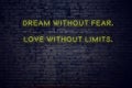 Positive inspiring quote on neon sign against brick wall dream without fear love without limits