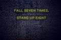 Positive inspiring quote on neon sign against brick wall fall seven times stand up eight