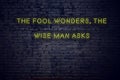 Positive inspiring quote on neon sign against brick wall the fool wonders the wise man asks