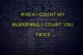 Positive inspiring quote on neon sign against brick wall when i count my blessings i count you twice