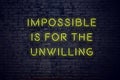 Positive inspiring quote on neon sign against brick wall impossible is for the unwilling