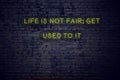 Positive inspiring quote on neon sign against brick wall life is not fair get used to it Royalty Free Stock Photo