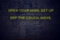 Positive inspiring quote on neon sign against brick wall open your mind get up off the couch move Royalty Free Stock Photo