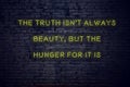 Positive inspiring quote on neon sign against brick wall the truth isnt always beauty but the hunger for it is