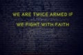 Positive inspiring quote on neon sign against brick wall we are twice armed if we fight with faith