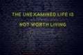 Positive inspiring quote on neon sign against brick wall the unexamined life is not worth living