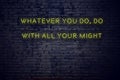 Positive inspiring quote on neon sign against brick wall whatever you do do with all your might