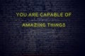 Positive inspiring quote on neon sign against brick wall you are capable of amazing things Royalty Free Stock Photo