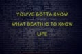 Positive inspiring quote on neon sign against brick wall youve gotta know what death is to know life Royalty Free Stock Photo