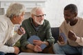 Positive interracial pensioners playing cards at Royalty Free Stock Photo