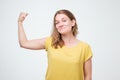 Positive joyful european woman showing hand muscles. Middle aged Caucasian woman in casual wear flexing bicep