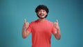 Positive latin spanish young man winking and showing thumbs up. Handsome successful man holding thumbs up and looking at Royalty Free Stock Photo