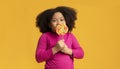 Positive little afro girl licking lollipop candy, enjoying sugar treat Royalty Free Stock Photo