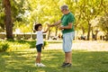 Positive little black boy and old caucasian grandfather enjoy free time, have fun, play football Royalty Free Stock Photo