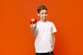 Positive little boy offering fresh red apple on camera