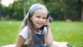 Positive little child girl having conversation on her mobile phone in summer park. Young female kid talking on sellphone Royalty Free Stock Photo