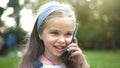 Positive little child girl having conversation on her mobile phone in summer park. Young female kid talking on sellphone Royalty Free Stock Photo