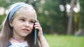 Positive little child girl having conversation on her mobile phone in summer park. Young female kid talking on sellphone Royalty Free Stock Photo