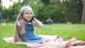 Positive little child girl having conversation on her mobile phone in summer park. Young female kid talking on sellphone Royalty Free Stock Photo