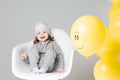 Positive little girl in gray suite with yellow ballon with smile.