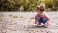 Positive little girl playing in the autumn park. Happy emotional child catches maple leaves. active holiday in autumn. leaf fall