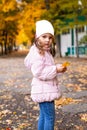 Positive little girl playing in the autumn park. Happy emotional child catches maple leaves. active holiday in autumn. leaf fall