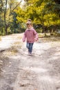 Positive little girl playing in the autumn park. Happy emotional child catches maple leaves. active holiday in autumn. leaf fall