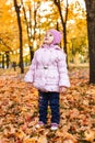 Positive little girl playing in the autumn park. Happy emotional child catches maple leaves. active holiday in autumn. leaf fall