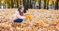 Positive little girl playing in the autumn park. Happy emotional child catches maple leaves and laughs. active holiday in autumn.