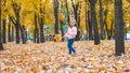 Positive little girl playing in the autumn park. Happy emotional child catches maple leaves and laughs. active holiday in autumn.