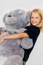 Positive little girl teddy bear in the hands of fun on a light background Royalty Free Stock Photo