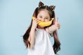 Positive looking tween girl with cat ears holding banana over mouth as a smile