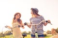 Positive lovely happy girls with hat ride bicycles on the park Royalty Free Stock Photo