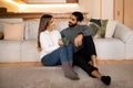 Positive lovers young european female and arab husband sit on floor, enjoy romantic date Royalty Free Stock Photo