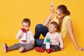 A positive loving mom cares her twin daughters, sits on the floor, being happy to spend time with little babies. Cheerful merry Royalty Free Stock Photo