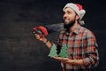 Positive male holds fir tree and handsaw. Royalty Free Stock Photo