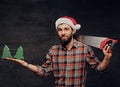 Positive male holds fir tree and handsaw. Royalty Free Stock Photo